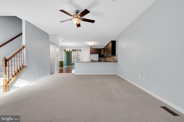 unfurnished living room featuring ceiling fan with notable chandelier and carpet floors