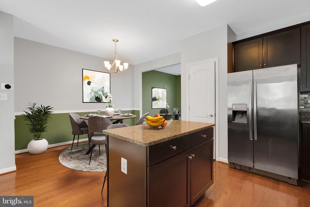 kitchen featuring a center island, stainless steel refrigerator with ice dispenser, hanging light fixtures, light wood-type flooring, and dark brown cabinets