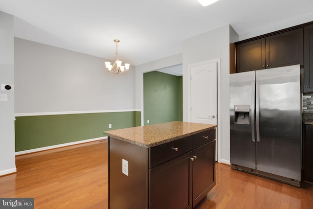 kitchen featuring light hardwood / wood-style floors, a kitchen island, dark brown cabinetry, hanging light fixtures, and stainless steel fridge