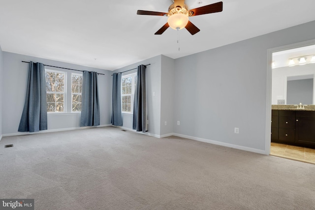 carpeted spare room featuring ceiling fan and sink