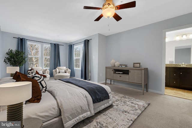 bedroom with ceiling fan, light colored carpet, connected bathroom, and sink