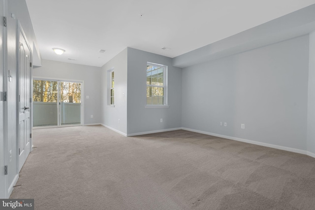 unfurnished room with light colored carpet and a healthy amount of sunlight