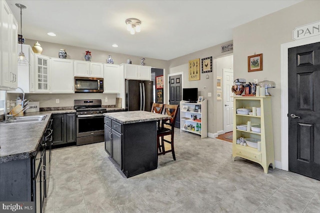 kitchen featuring a breakfast bar, decorative light fixtures, a kitchen island, white cabinetry, and stainless steel appliances