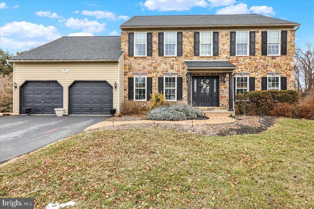 colonial inspired home featuring a garage and a front lawn