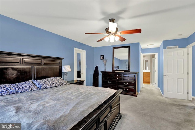 bedroom with ceiling fan, light colored carpet, and connected bathroom