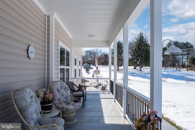 snow covered deck featuring covered porch