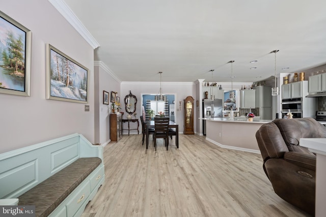 living room with a chandelier, ornamental molding, and light hardwood / wood-style floors