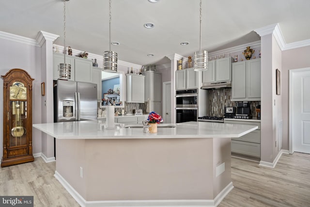 kitchen featuring a kitchen island with sink, tasteful backsplash, pendant lighting, gray cabinetry, and appliances with stainless steel finishes