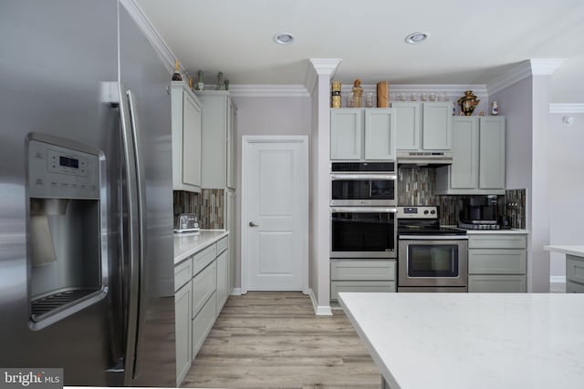 kitchen with stainless steel appliances, light hardwood / wood-style flooring, crown molding, and decorative backsplash