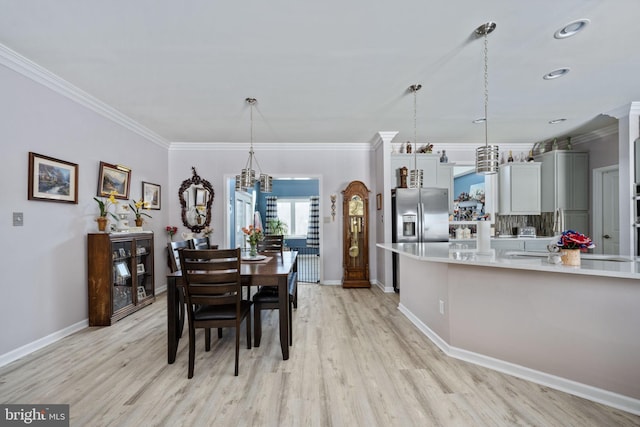 dining space with light hardwood / wood-style floors, a notable chandelier, and crown molding