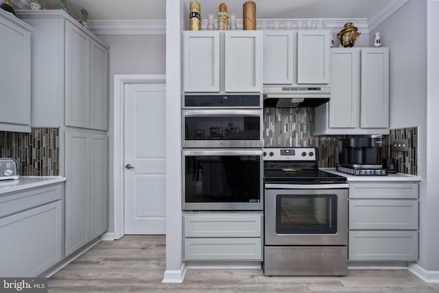 kitchen featuring stainless steel appliances, decorative backsplash, crown molding, and light hardwood / wood-style flooring