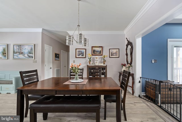 dining room featuring an inviting chandelier, ornamental molding, and light hardwood / wood-style floors