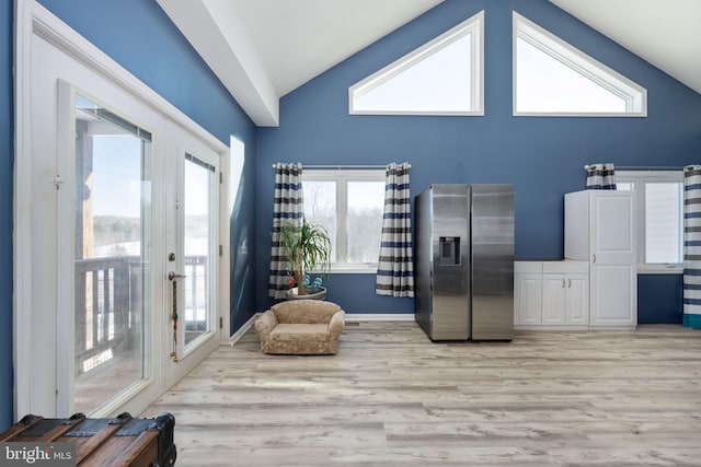 interior space featuring stainless steel fridge, light wood-type flooring, and high vaulted ceiling