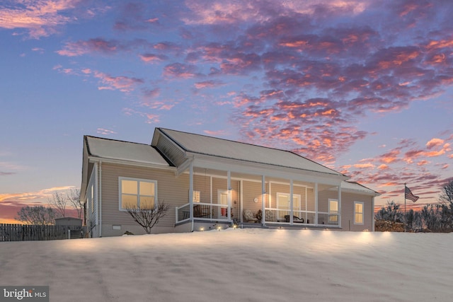 back house at dusk featuring covered porch