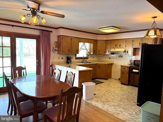 kitchen featuring kitchen peninsula, ornamental molding, sink, black appliances, and hanging light fixtures