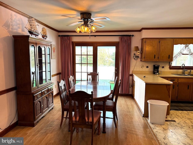 dining area with ceiling fan, sink, light hardwood / wood-style floors, and ornamental molding