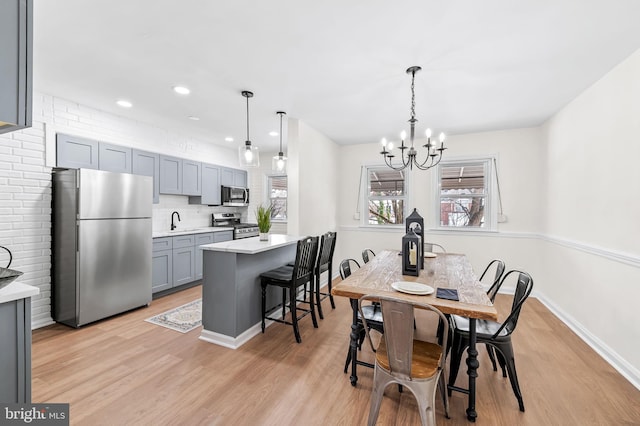 dining space featuring sink, light hardwood / wood-style flooring, and an inviting chandelier