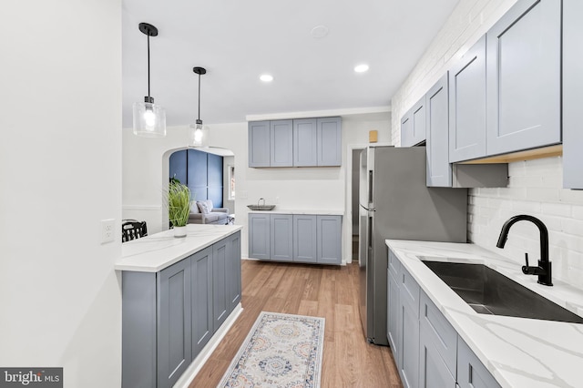 kitchen featuring gray cabinetry, decorative light fixtures, sink, and light hardwood / wood-style flooring