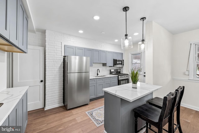 kitchen featuring decorative light fixtures, stainless steel appliances, light hardwood / wood-style flooring, and sink