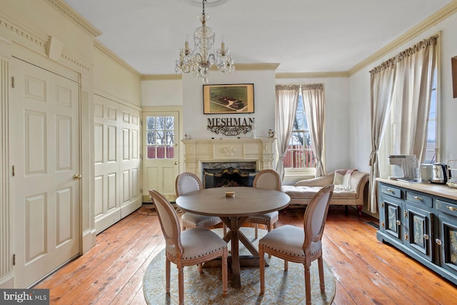 dining room with ornamental molding, light hardwood / wood-style floors, and an inviting chandelier