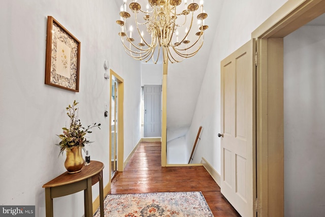 corridor featuring dark hardwood / wood-style flooring, a high ceiling, and an inviting chandelier