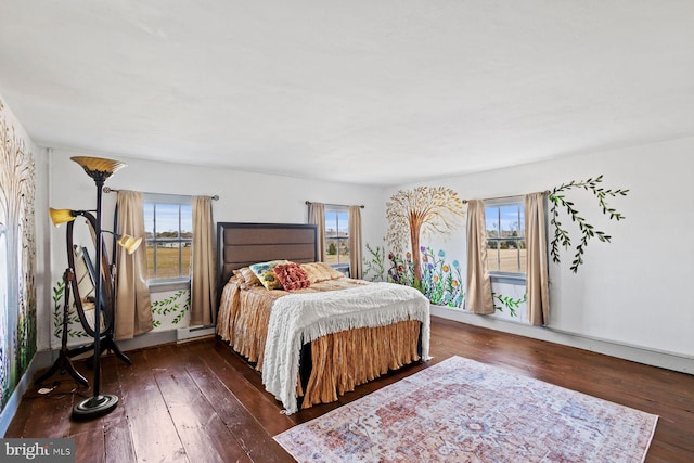 bedroom featuring a baseboard heating unit, multiple windows, and dark wood-type flooring