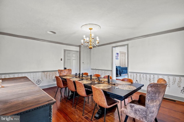 dining area featuring dark hardwood / wood-style floors, ornamental molding, and an inviting chandelier