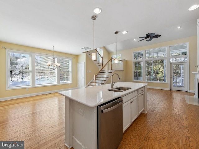 kitchen featuring white cabinetry, sink, stainless steel dishwasher, a kitchen island with sink, and ceiling fan with notable chandelier