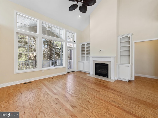 unfurnished living room with ceiling fan, high vaulted ceiling, and light hardwood / wood-style floors