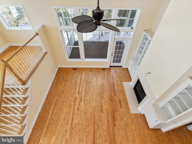 unfurnished living room with ceiling fan, plenty of natural light, and a towering ceiling