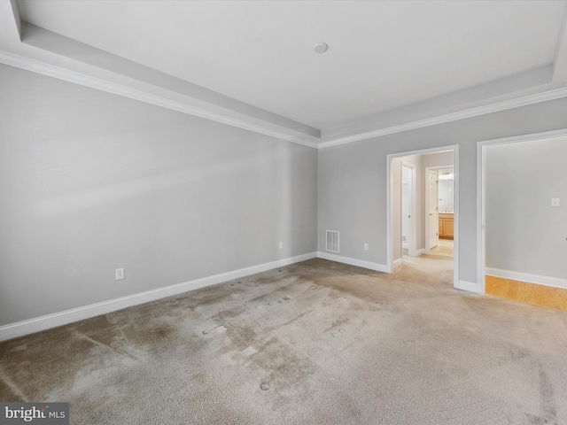 carpeted spare room with a raised ceiling and ornamental molding