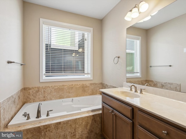 bathroom featuring vanity, tiled bath, and a healthy amount of sunlight