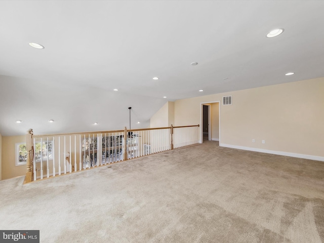 spare room with light colored carpet and vaulted ceiling