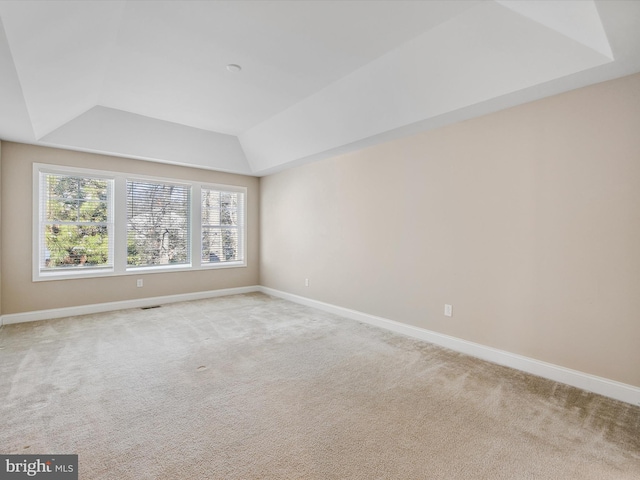 carpeted empty room featuring a tray ceiling