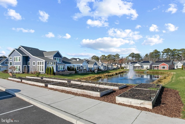 view of home's community with a water view and a lawn