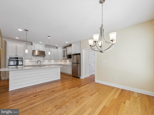 kitchen featuring pendant lighting, backsplash, sink, white cabinetry, and stainless steel appliances