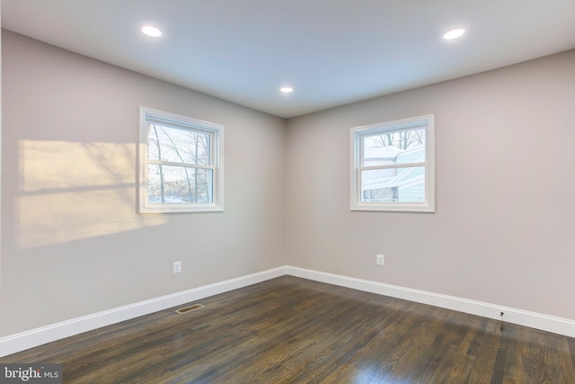 unfurnished room featuring dark hardwood / wood-style flooring and a healthy amount of sunlight