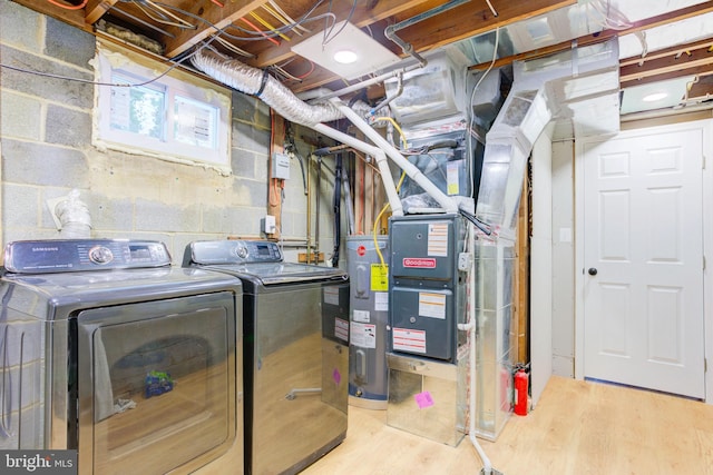 laundry room with washer and dryer, electric water heater, and light hardwood / wood-style flooring