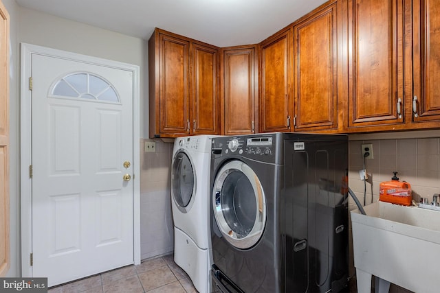 laundry area featuring light tile patterned floors, cabinets, washer and clothes dryer, and sink