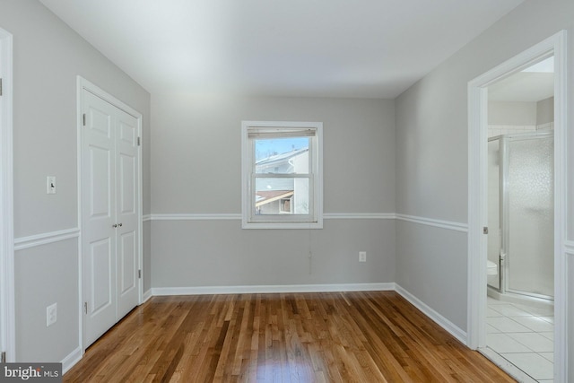 unfurnished bedroom featuring light hardwood / wood-style floors, a closet, and ensuite bath