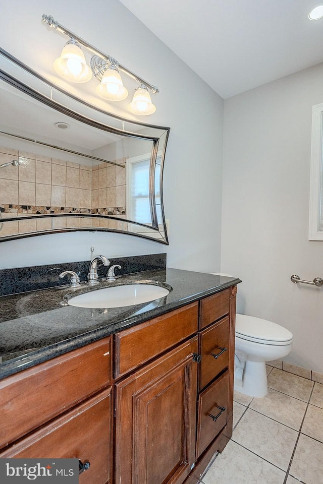 bathroom with toilet, vanity, and tile patterned flooring