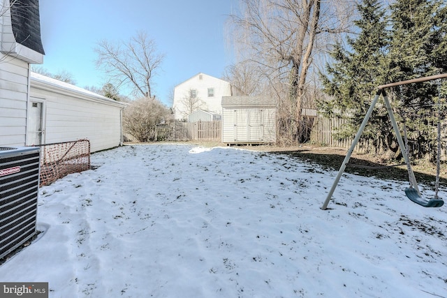 yard layered in snow with a storage unit and central AC