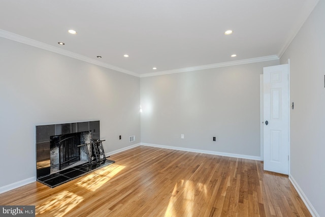 unfurnished living room with hardwood / wood-style flooring, a tile fireplace, and crown molding