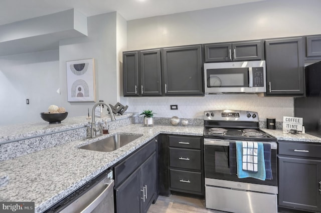 kitchen with light stone countertops, sink, and appliances with stainless steel finishes