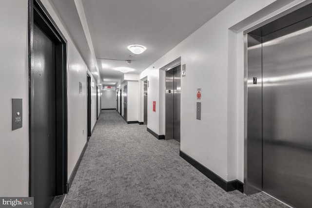 hallway featuring elevator and dark colored carpet