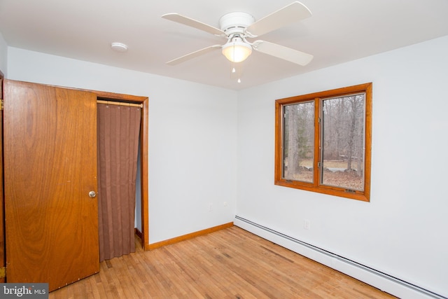 unfurnished room with ceiling fan, light hardwood / wood-style flooring, and a baseboard heating unit