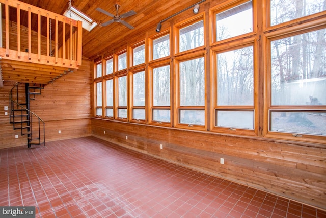 unfurnished living room with wood ceiling, high vaulted ceiling, ceiling fan, and wood walls