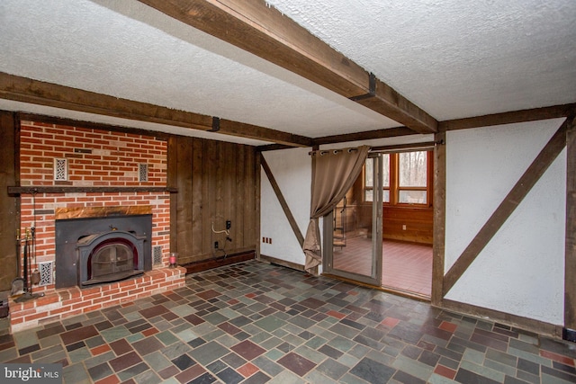 unfurnished living room with beam ceiling, a textured ceiling, and wooden walls