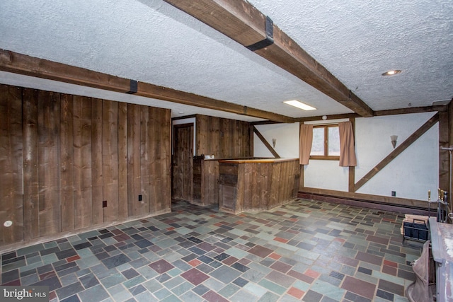 basement featuring wood walls and a textured ceiling