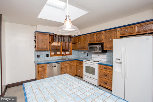 kitchen featuring sink, hanging light fixtures, a skylight, tile counters, and stainless steel appliances